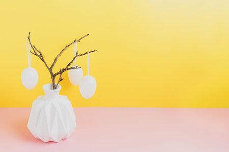 Happy Easter holiday, coming spring concept. Tree branches, flower twigs in white vase or jar with...