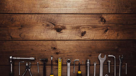 Flat lay with various work tools on wooden background working table. Top view on new hand tool set for repair, construction kit, overhead. Must-have for men. Equipment for building. Industry conceptの写真素材
