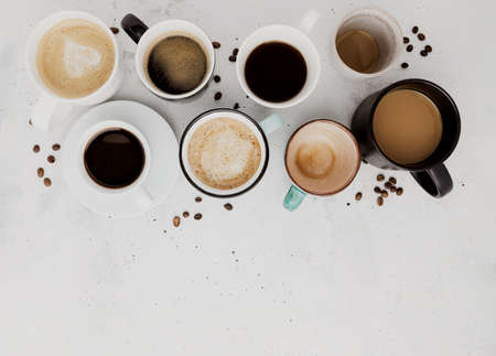 Top view on flat lay with many different full and empty coffee cups composition on gray white concrete background. Variety of tea mug collection layout. Dried coffee beans. Espresso, latte, americanoの写真素材