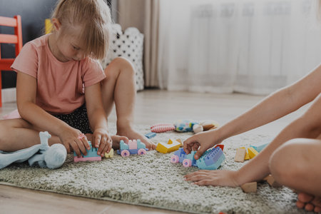 Children playing with colorful plastic toy colourful train. Kids sitting on carpet indoors at sunny white home bedroom or kindergarten, nursery. Funny educational eco-friendly game for childの写真素材