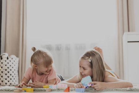 Children playing with colorful toys. Kids lying on carpet at home bedroom or kindergarten. Development of fine motor skills, imagination, logical thinking concept. Educational eco-friendly gamesの写真素材