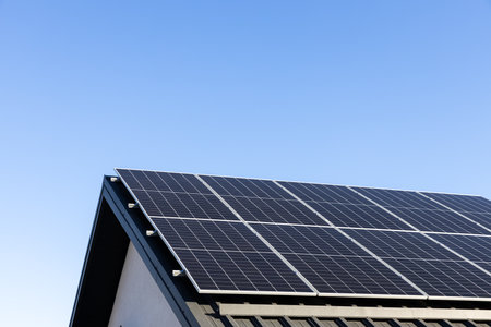 Modern house with solar panels stand-alone photovoltaic plant system on household metal sheet rooftop. Clear blue sky background. Clean alternative energy concept. Professional installation, go greenの写真素材