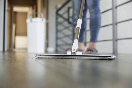 Woman mopping, wiping sleek hardwood floor in modern home setting. Housewife use cleaning mop in cozy living house room. Housekeeping, housework. Sanitation, cleanliness, hygiene, cleanup, maintenanceの写真素材