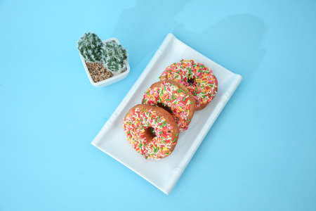 Pile of doughnuts in the powder give fine sugar, there are cactus tree accessories set in light blueの写真素材