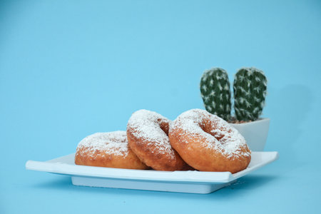 Pile of doughnuts in the powder give fine sugar, there are cactus tree accessories set in light blueの写真素材