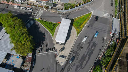 crossroads with several vehicles, in the middle of the intersection there is a building.のeditorial素材