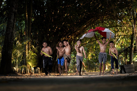 Concept photo of village children who are excited and play in the Indonesian independence edition carrying the flag. : Bantul, Indonesia - 15 August 2021のeditorial素材