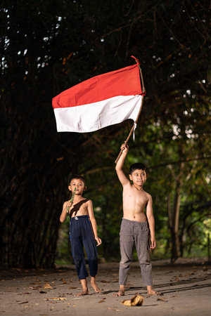 Concept photo of village children who are excited and play in the Indonesian independence edition carrying the flag. : Bantul, Indonesia - 15 August 2021のeditorial素材