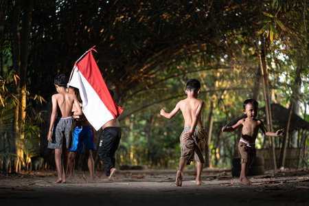 Concept photo of village children who are excited and play in the Indonesian independence edition carrying the flag. : Bantul, Indonesia - 15 August 2021のeditorial素材
