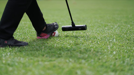 The gateball player's feet and their tools on the grass field.