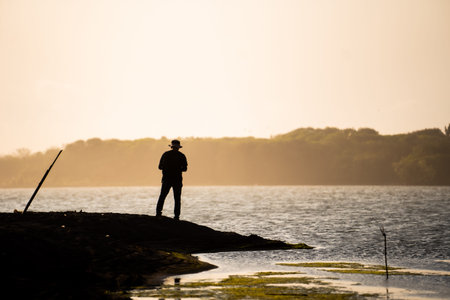 silhouette of an adventurer walking by the seashore and taking pictures, sunset view. motivational...
