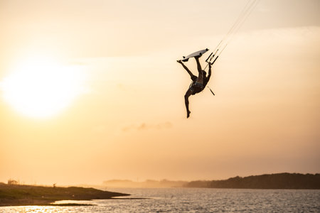 kitesurfing. A surfer rides on a beautiful backdrop of bridges and coastline at sunset and performs all kinds of stunts. : Yogyakarta, Indonesia - 26 August 2023のeditorial素材