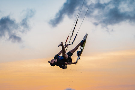 kitesurfing. A surfer rides on a beautiful backdrop of bridges and coastline at sunset and performs all kinds of stunts. : Yogyakarta, Indonesia - 26 August 2023のeditorial素材