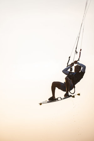 kitesurfing. A surfer rides on a beautiful backdrop of bridges and coastline at sunset and performs...