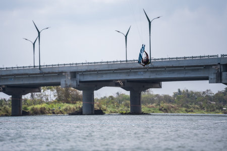 kitesurfing. A surfer rides against a backdrop of beautiful bridges and coastlines and performs all kinds of stunts. Sport, health, leisure concept. : Yogyakarta, Indonesia - 26 August 2023のeditorial素材