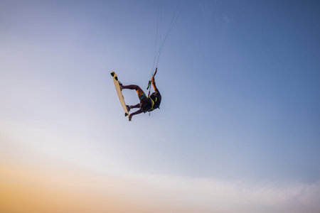 kitesurfing. A surfer rides on a beautiful backdrop of bridges and coastline at sunset and performs...