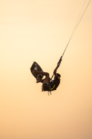 kitesurfing. A surfer rides on a beautiful backdrop of bridges and coastline at sunset and performs all kinds of stunts. : Yogyakarta, Indonesia - 26 August 2023のeditorial素材