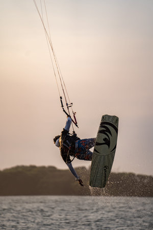 kitesurfing. A surfer rides on a beautiful backdrop of bridges and coastline at sunset and performs all kinds of stunts. : Yogyakarta, Indonesia - 26 August 2023のeditorial素材