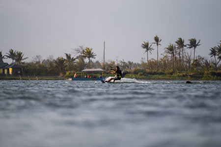 kitesurfing. A surfer rides against a backdrop of beautiful bridges and coastlines and performs all kinds of stunts. Sport, health, leisure concept. : Yogyakarta, Indonesia - 26 August 2023のeditorial素材