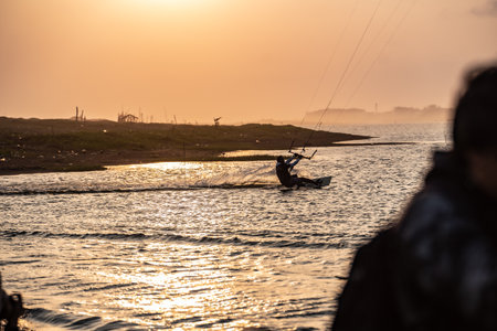 kitesurfing. A surfer rides on a beautiful backdrop of bridges and coastline at sunset and performs all kinds of stunts. : Yogyakarta, Indonesia - 26 August 2023のeditorial素材