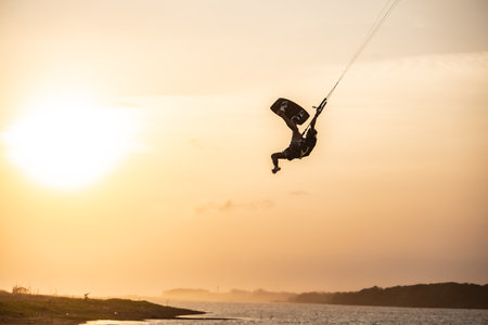 kitesurfing. A surfer rides on a beautiful backdrop of bridges and coastline at sunset and performs all kinds of stunts. : Yogyakarta, Indonesia - 26 August 2023のeditorial素材