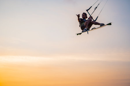 kitesurfing. A surfer rides on a beautiful backdrop of bridges and coastline at sunset and performs all kinds of stunts. : Yogyakarta, Indonesia - 26 August 2023のeditorial素材