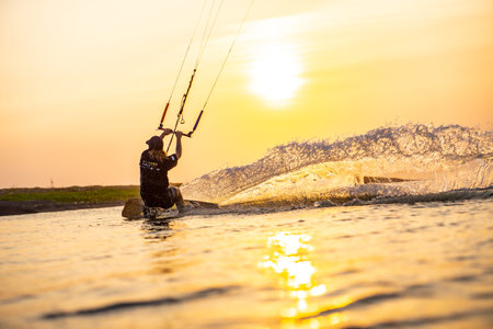 kitesurfing. A surfer rides on a beautiful backdrop of bridges and coastline at sunset and performs...