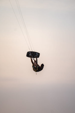 kitesurfing. A surfer rides on a beautiful backdrop of bridges and coastline at sunset and performs...
