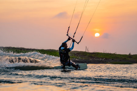 kitesurfing. A surfer rides on a beautiful backdrop of bridges and coastline at sunset and performs all kinds of stunts. : Yogyakarta, Indonesia - 26 August 2023のeditorial素材