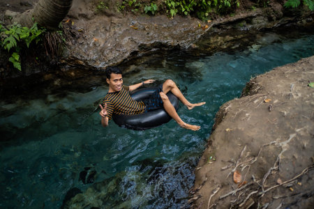 tourists play and enjoy swimming as well as using float tubes, being in the spring river. Udal Gumuk...