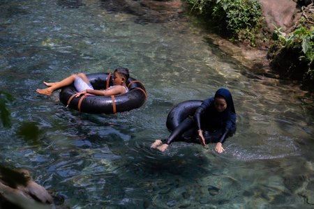 tourists play and enjoy swimming as well as using float tubes, being in the spring river. Udal Gumuk...