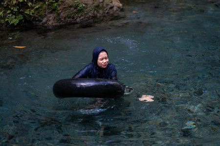 tourists play and enjoy swimming as well as using float tubes, being in the spring river. Udal Gumuk river, Magelang, Central Java, Indonesia. : Magelang, Indonesia - 31 August 2023のeditorial素材