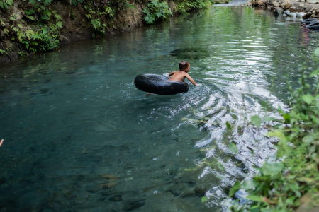 A child plays and swims in the river using a float. Udal Gumuk river, Magelang, Central Java,...