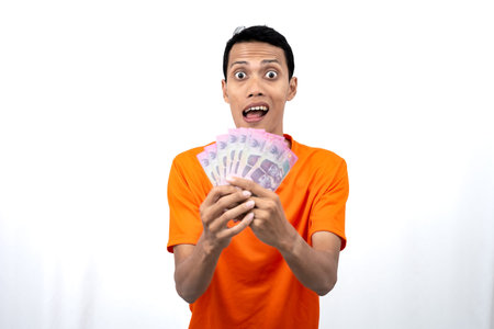 Portrait of a young Asian man wearing an orange t-shirt with a happy, surprised, pleased expression...