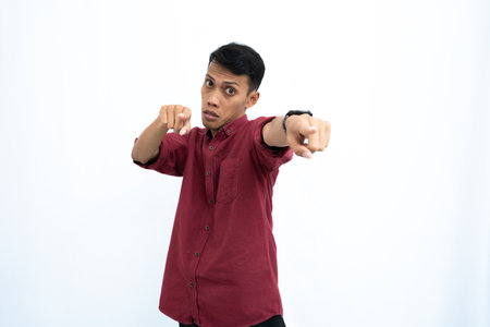Asian man, businessman or student concept wearing red casual clothes poses pointing at you. Isolated white background.の写真素材