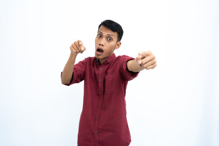 Asian man, businessman or student concept wearing red casual clothes poses pointing at you. Isolated white background.の写真素材