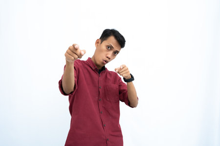 Asian man, businessman or student concept wearing red casual clothes poses pointing at you. Isolated white background.の写真素材
