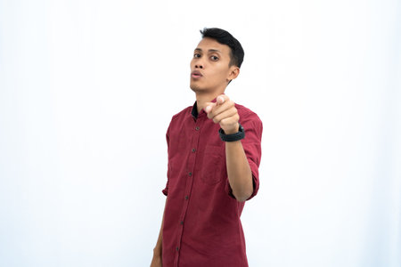 Asian man, businessman or student concept wearing red casual clothes poses pointing at you. Isolated white background.の写真素材