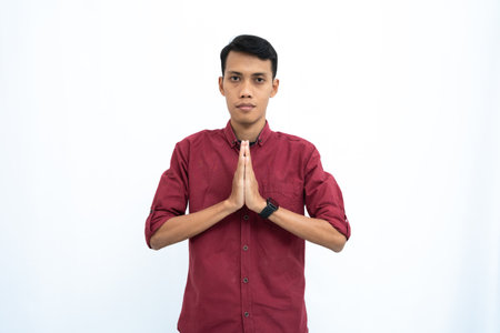 asian man, businessman or student concept wearing red casual shirt giving warm greeting pose. Isolated white background.の写真素材
