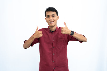 asian man, man or student concept wearing red casual shirt showing thumbs up that agree, okay. Isolated white background.の写真素材