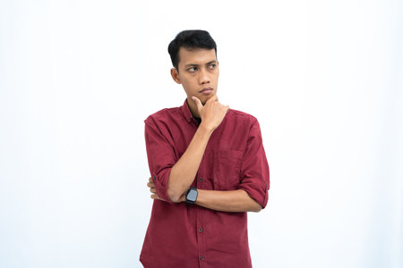 asian man, business or student concept wearing red casual shirt thinking pose, looking for ideas, getting ideas, confused. Isolated white background.の写真素材