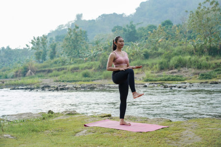 A slender, tanned Asian girl in sportswear performs high-knee stretches outdoors on a beautiful...