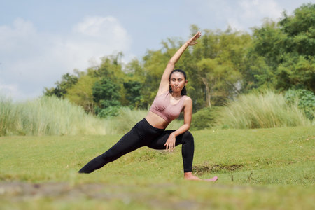 Mental and physical health. A slender, Asian girl in sportswear does yoga by a calm river in the...