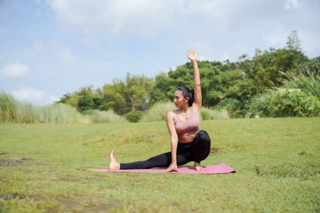 Mental and physical health. A woman in sportswear does yoga in the morning. The woman stands in a warrior pose with her arms outstretched.の写真素材