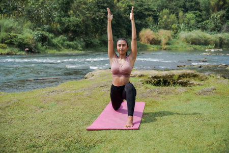 Mental and physical health. A slender, tanned Asian woman in athletic attire performs yoga outdoors...