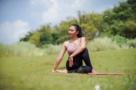 Mental and physical health. A slender, tanned woman in sportswear performs yoga outdoors in a...