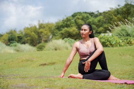 Mental and physical health. A slender, tanned Asian woman in sportswear performs yoga outdoors in a...