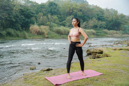 A slender Asian girl with brown skin in sportswear doing stretching movements and rotating her body...