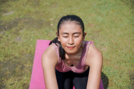 Mental and physical health. A woman in sportswear practices yoga by a tranquil river in the morning....