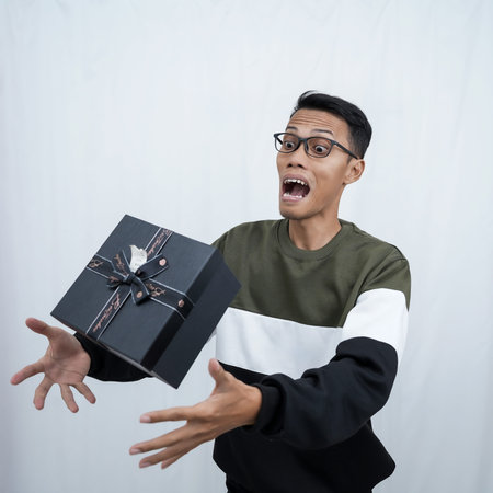 An Asian young man with glasses wearing a sweater with a surprised happy expression getting a...